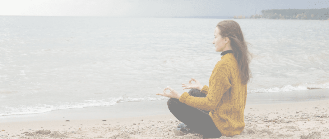 Frau meditiert nahe am Strand nahe zum Meer